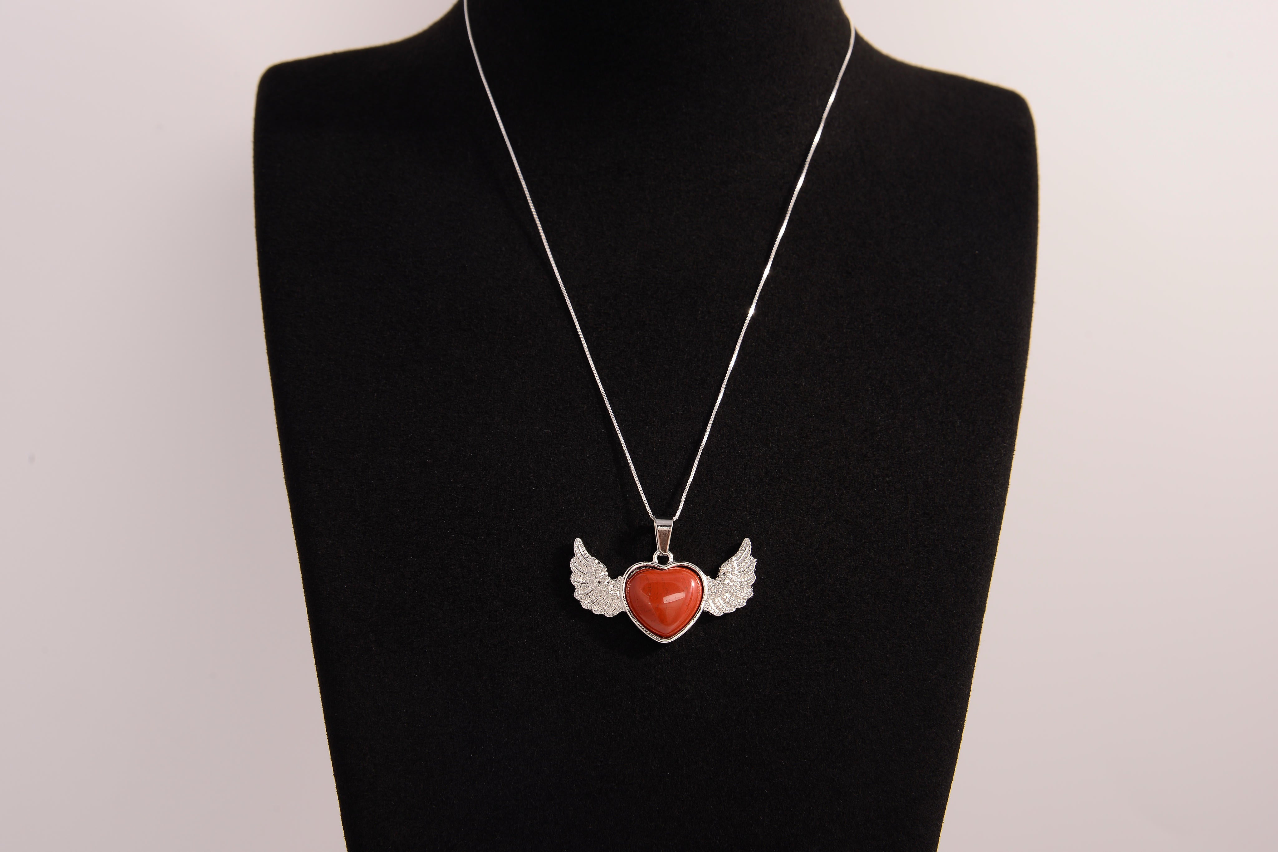 Raw Earth Crystals carnelian heart with wings necklace, featuring a vibrant orange-red heart-shaped stone adorned with delicate angelic wings, designed to boost energy, enhance motivation, and support emotional strength.