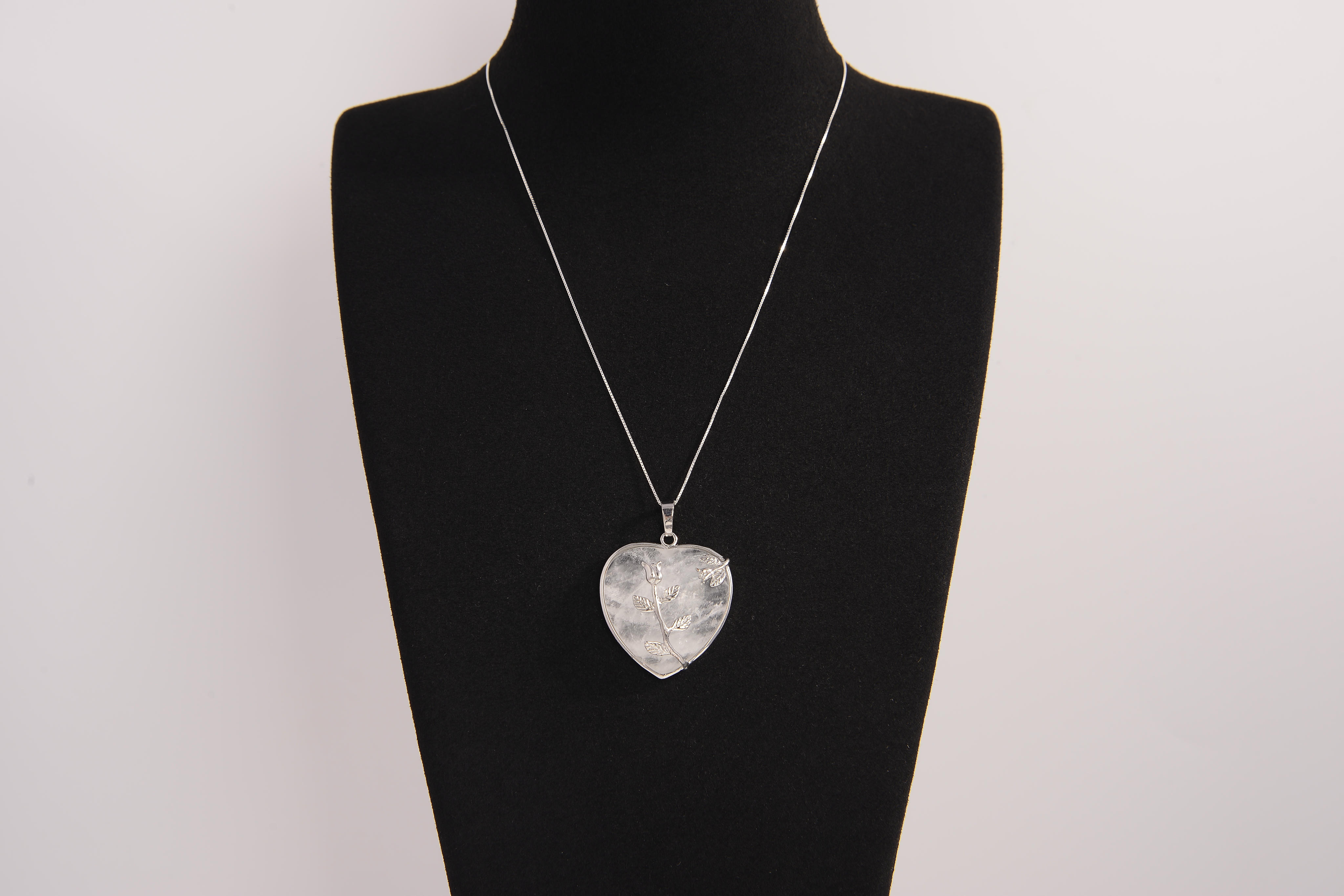 Raw Earth Crystals clear quartz heart pendant with an elegant rose design, featuring a delicate silver-tone stem and leaves embedded in natural clear quartz, promoting clarity, love, and spiritual connection.