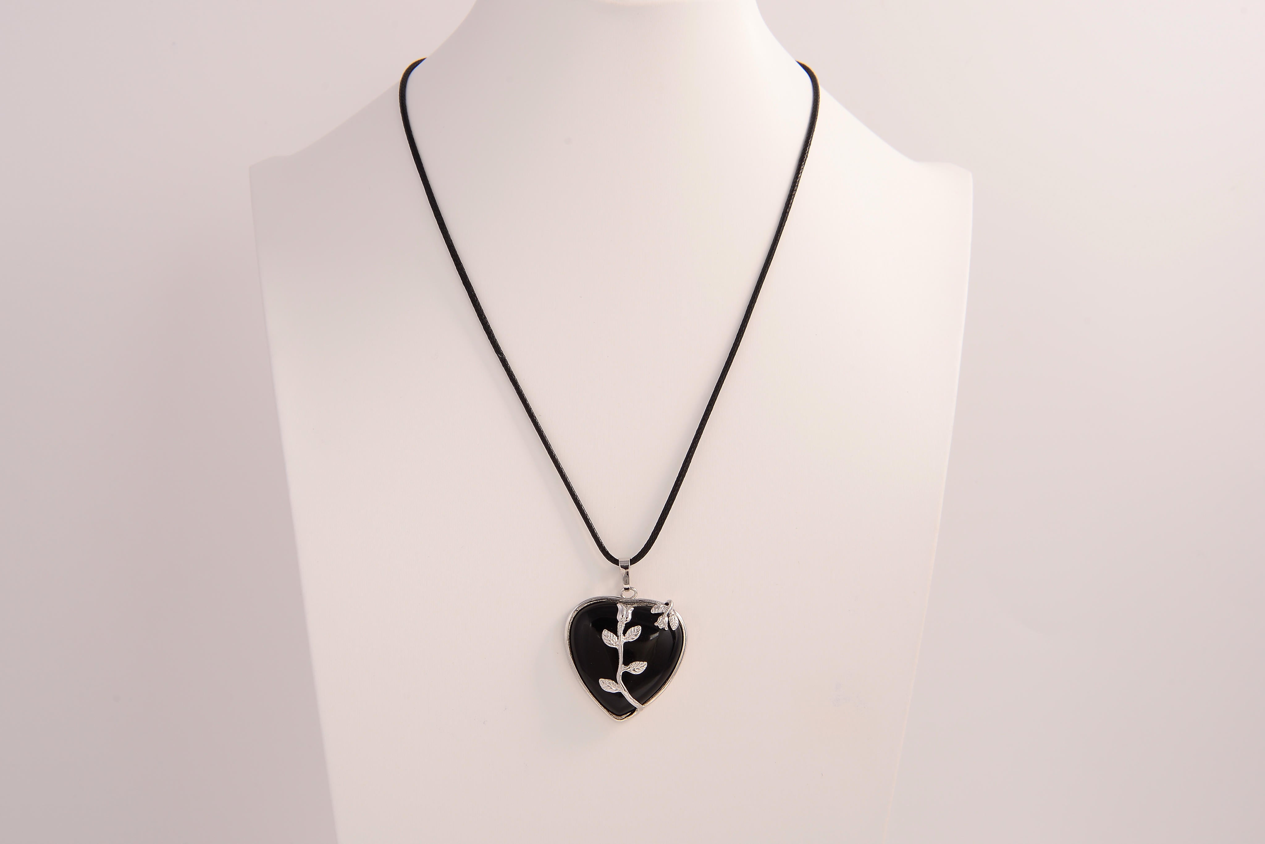 Raw Earth Crystals obsidian heart pendant with an elegant rose design, featuring a sleek black obsidian stone and a silver-tone vine with leaves, promoting protection, grounding, and emotional strength.