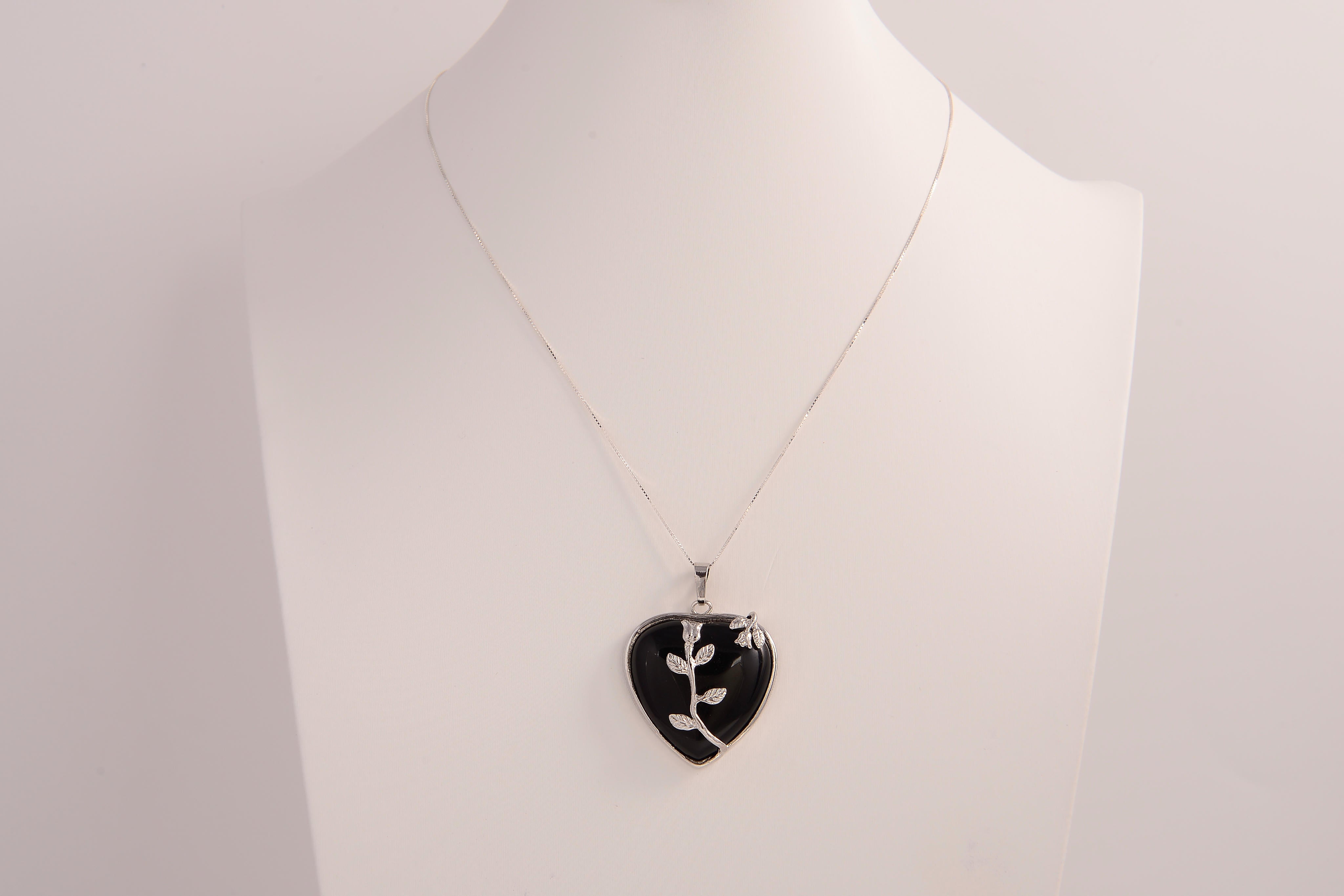 Raw Earth Crystals obsidian heart pendant with an elegant rose design, featuring a sleek black obsidian stone and a silver-tone vine with leaves, promoting protection, grounding, and emotional strength.