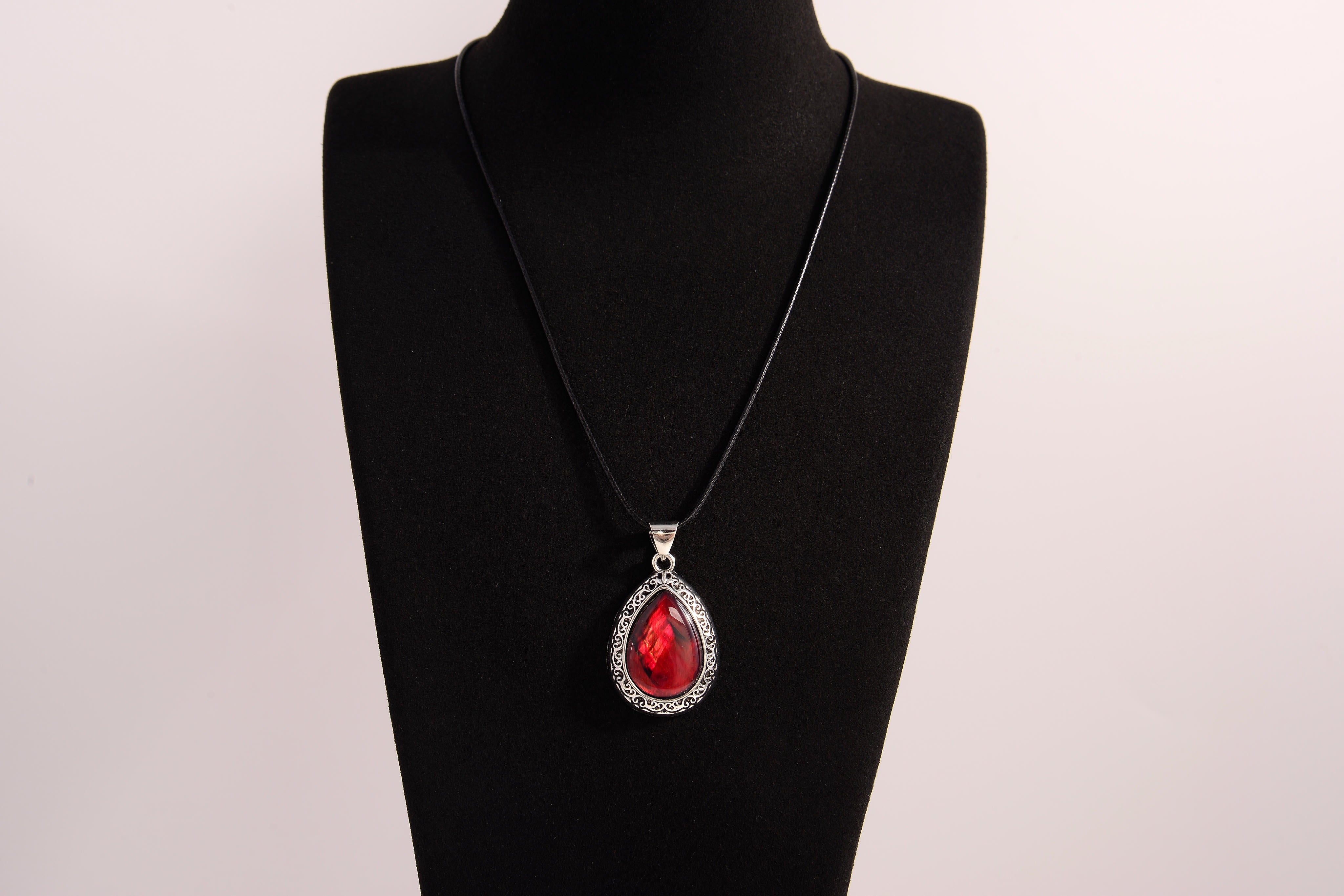 Raw Earth Crystals red agate pendant with a teardrop-shaped design, featuring natural red agate and an ornate silver-tone setting, promoting courage, vitality, and emotional strength.