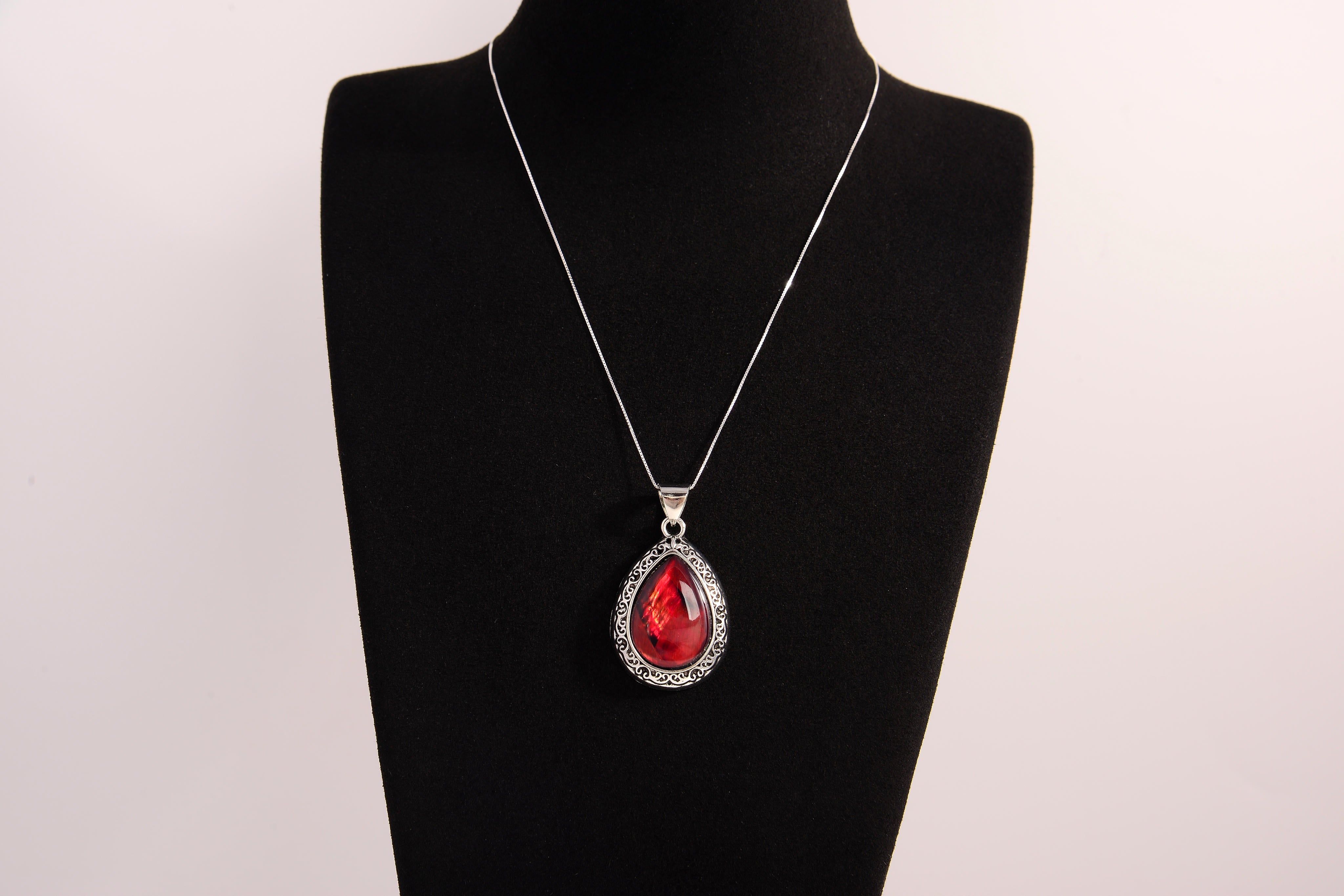 Raw Earth Crystals red agate pendant with a teardrop-shaped design, featuring natural red agate and an ornate silver-tone setting, promoting courage, vitality, and emotional strength.