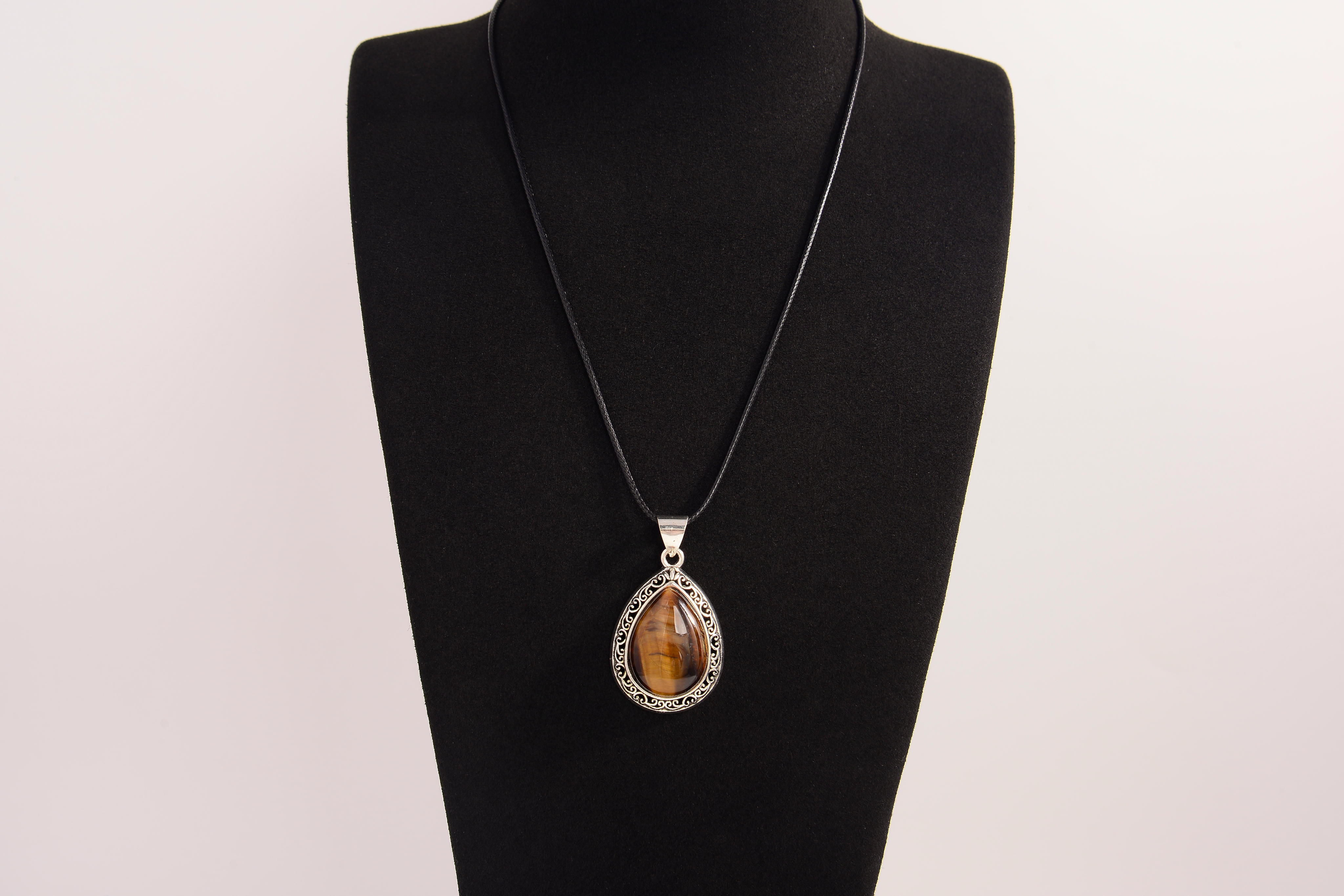 Raw Earth Crystals tiger eye pendant with a teardrop-shaped design, featuring natural tiger eye and an ornate silver-tone setting, promoting confidence, focus, and protection.