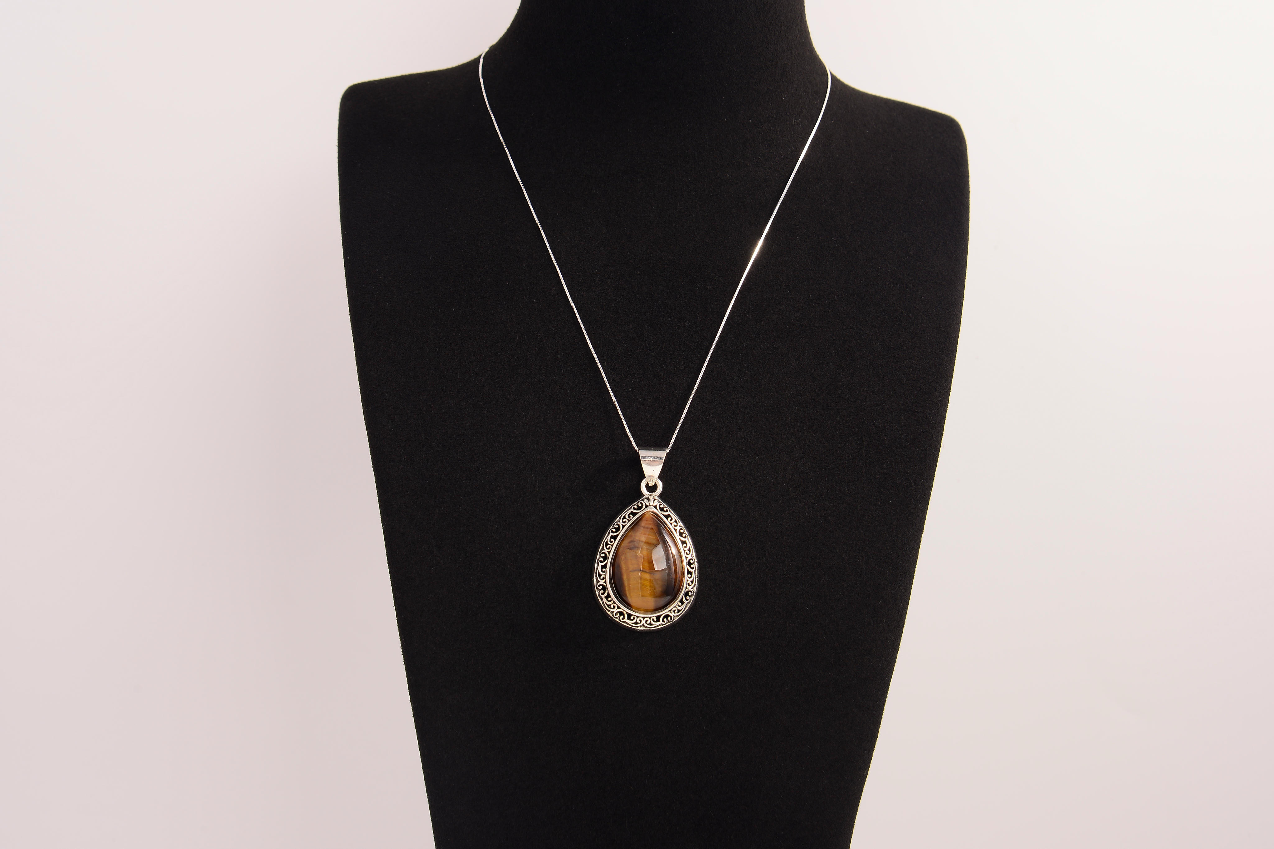 Raw Earth Crystals tiger eye pendant with a teardrop-shaped design, featuring natural tiger eye and an ornate silver-tone setting, promoting confidence, focus, and protection.