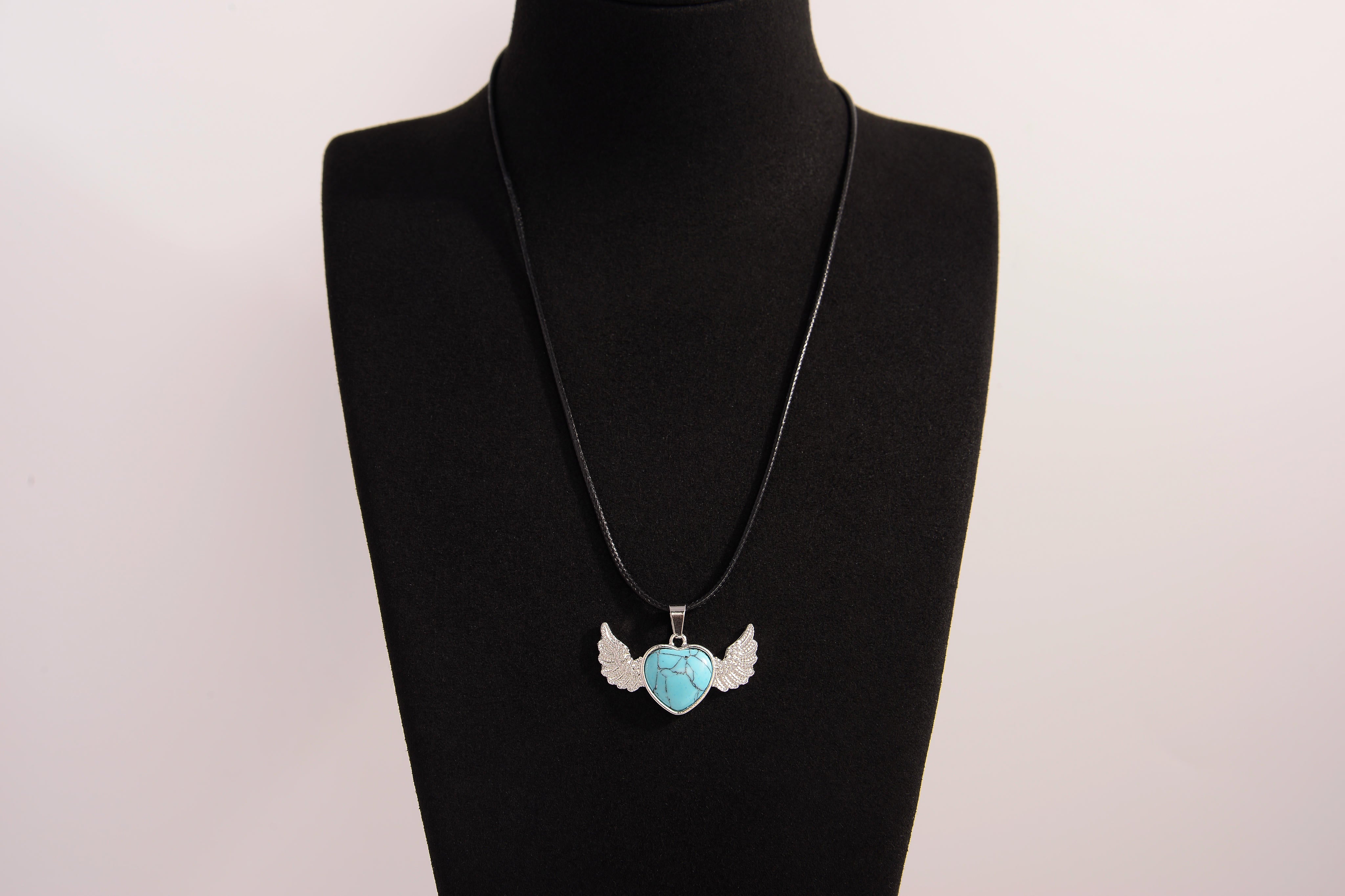 Raw Earth Crystals turquoise heart with wings necklace, featuring a vibrant blue-green heart-shaped stone adorned with delicate angelic wings, designed to promote communication, emotional balance, and spiritual protection.