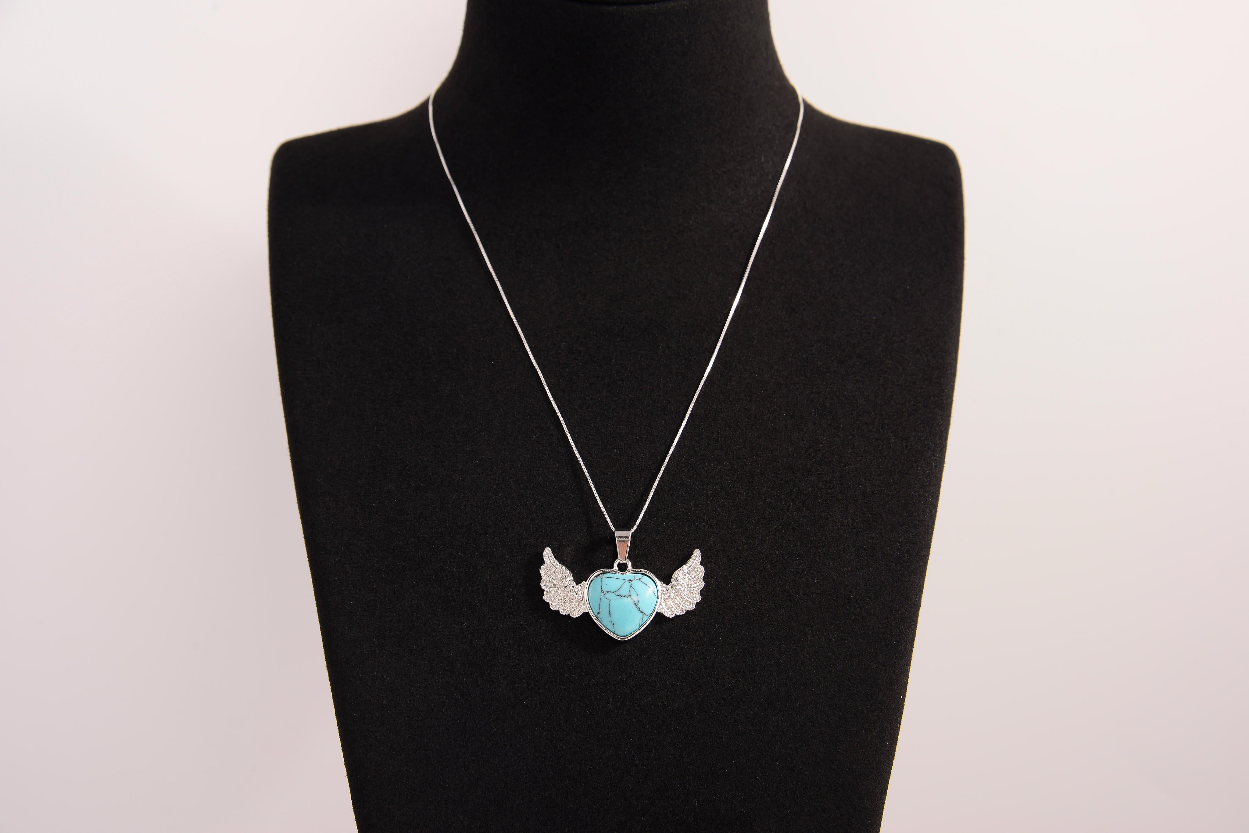 Raw Earth Crystals turquoise heart with wings necklace, featuring a vibrant blue-green heart-shaped stone adorned with delicate angelic wings, designed to promote communication, emotional balance, and spiritual protection.