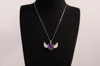 Raw Earth Crystals amethyst heart with wings necklace, featuring a deep purple heart-shaped stone adorned with delicate angelic wings, designed to enhance intuition, promote spiritual growth, and support inner peace.