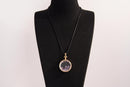 Raw Earth Crystals amethyst pendant with a crystal-encased design, featuring natural amethyst and gold-tone setting, enhancing intuition, calmness, and spiritual awareness.