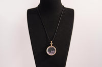 Raw Earth Crystals amethyst pendant with a crystal-encased design, featuring natural amethyst and gold-tone setting, enhancing intuition, calmness, and spiritual awareness.