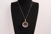 Raw Earth Crystals amethyst pendant with a crystal-encased design, featuring natural amethyst and gold-tone setting, enhancing intuition, calmness, and spiritual awareness.