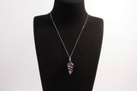 Raw Earth Crystals amethyst pendant with a spiral wire wrap design, crafted from natural stone to support spiritual growth, intuition, and inner peace.