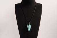 Raw Earth Crystals angel pendant crafted from carved turquoise, featuring a vibrant blue-green hue with natural matrix patterns to promote communication, protection, and emotional balance.