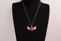 Raw Earth Crystals carnelian heart with wings necklace, featuring a vibrant orange-red heart-shaped stone adorned with delicate angelic wings, designed to boost energy, enhance motivation, and support emotional strength.