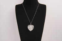 Raw Earth Crystals clear quartz heart pendant with an elegant rose design, featuring a delicate silver-tone stem and leaves embedded in natural clear quartz, promoting clarity, love, and spiritual connection.
