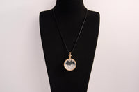 Raw Earth Crystals clear quartz pendant with a crystal-encased design, featuring natural clear quartz and gold-tone setting, enhancing clarity, healing, and spiritual connection.