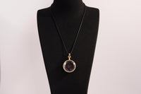 Raw Earth Crystals garnet pendant with a crystal-encased design, featuring natural garnet and gold-tone setting, promoting passion, vitality, and emotional strength.