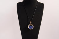 Raw Earth Crystals lapis pendant with a crystal-encased design, featuring natural lapis lazuli and gold-tone setting, promoting wisdom, communication, and inner truth.