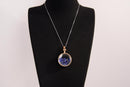 Raw Earth Crystals lapis pendant with a crystal-encased design, featuring natural lapis lazuli and gold-tone setting, promoting wisdom, communication, and inner truth.