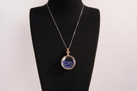 Raw Earth Crystals lapis pendant with a crystal-encased design, featuring natural lapis lazuli and gold-tone setting, promoting wisdom, communication, and inner truth.