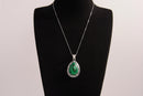 Raw Earth Crystals malachite pendant with a teardrop-shaped design, featuring natural malachite and an ornate silver-tone setting, promoting transformation, abundance, and emotional healing.