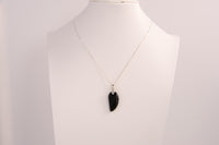 Raw Earth Crystals obsidian angel wing pendant, featuring a polished black obsidian stone carved into an elegant wing shape and set on a silver-tone chain, promoting protection, grounding, and spiritual connection.