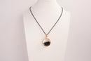 Raw Earth Crystals obsidian pendant with a crystal-encased design, featuring natural obsidian and gold-tone setting, promoting protection, grounding, and emotional balance.