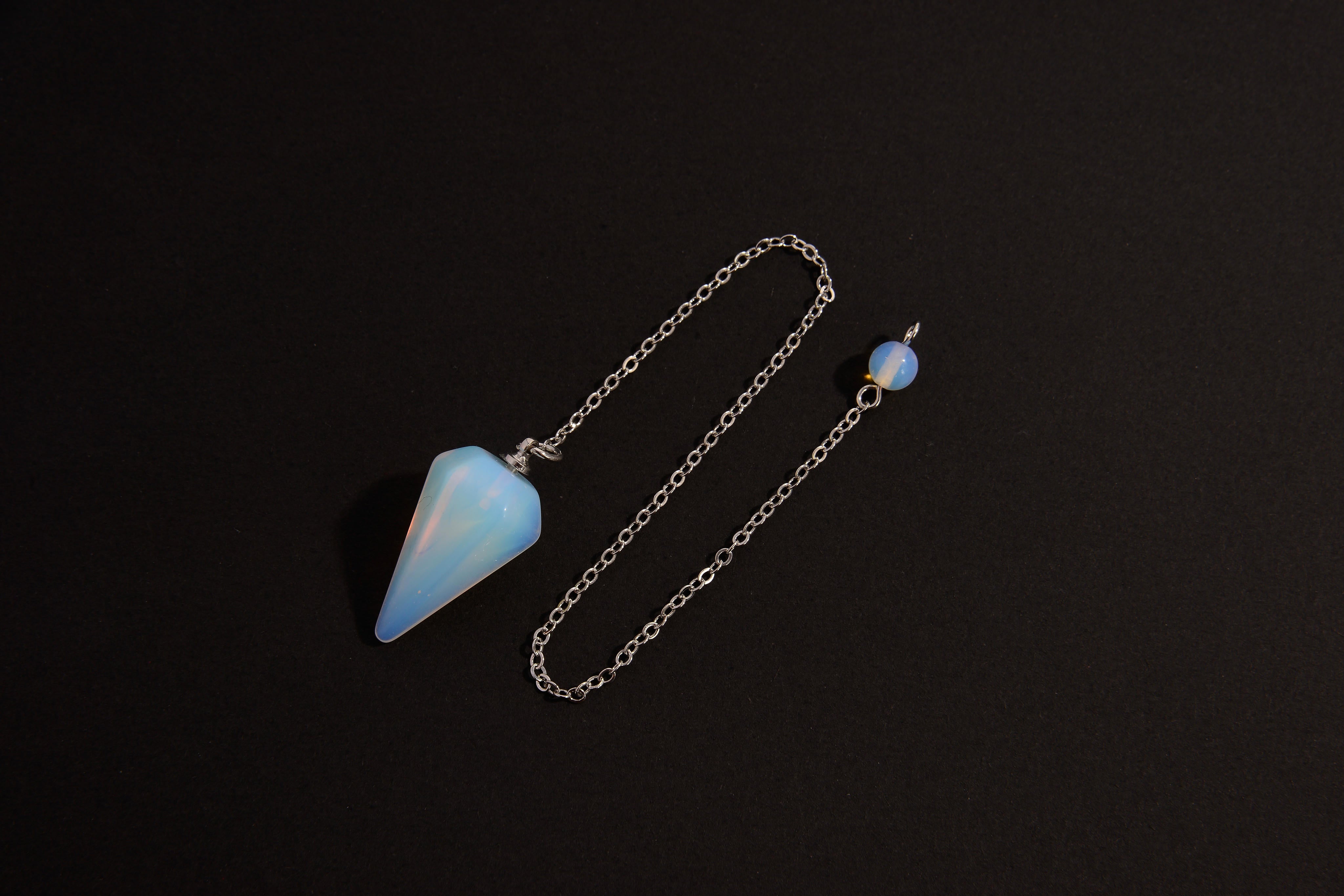 Raw Earth Crystals opal cone pendulum on silver chain, crafted from natural opal stone, enhancing intuition, spiritual insight, and energy balancing.