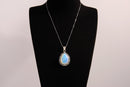 Raw Earth Crystals opalite pendant with a teardrop-shaped design, featuring natural opalite and an ornate silver-tone setting, enhancing emotional balance, intuition, and spiritual connection.
