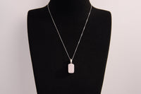 Raw Earth Crystals rectangle pendant featuring a polished rose quartz cabochon set in a sleek silver-toned bail, symbolizing love, compassion, and emotional healing.