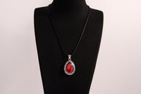 Raw Earth Crystals red agate pendant with a teardrop-shaped design, featuring natural red agate and an ornate silver-tone setting, promoting courage, vitality, and emotional strength.
