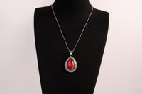 Raw Earth Crystals red agate pendant with a teardrop-shaped design, featuring natural red agate and an ornate silver-tone setting, promoting courage, vitality, and emotional strength.