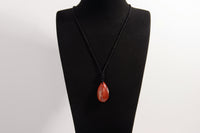 Raw Earth Crystals red jasper teardrop pendant on black cord, made from natural red jasper stone, supporting strength, courage, and emotional balance.
