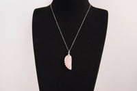 Raw Earth Crystals rose quartz pendant with an angel wing design, crafted from natural stone to encourage love, compassion, and emotional healing.