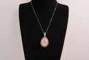 Raw Earth Crystals rose quartz pendant with a teardrop-shaped design, featuring natural rose quartz and an ornate silver-tone setting, promoting love, compassion, and emotional healing.