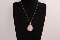 Raw Earth Crystals rose quartz pendant with a teardrop-shaped design, featuring natural rose quartz and an ornate silver-tone setting, promoting love, compassion, and emotional healing.
