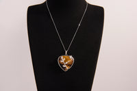 Raw Earth Crystals tiger eye heart pendant with an elegant rose design, featuring a rich golden-brown tiger eye stone and a silver-tone vine with leaves, promoting confidence, clarity, and personal power.