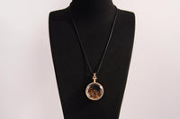 Raw Earth Crystals tiger eye pendant with a crystal-encased design, featuring natural tiger eye and gold-tone setting, supporting confidence, clarity, and personal power.