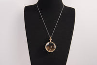 Raw Earth Crystals tiger eye pendant with a crystal-encased design, featuring natural tiger eye and gold-tone setting, supporting confidence, clarity, and personal power.