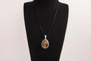 Raw Earth Crystals tiger eye pendant with a teardrop-shaped design, featuring natural tiger eye and an ornate silver-tone setting, promoting confidence, focus, and protection.