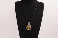 Raw Earth Crystals tiger eye pendant with a teardrop-shaped design, featuring natural tiger eye and an ornate silver-tone setting, promoting confidence, focus, and protection.