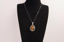 Raw Earth Crystals tiger eye pendant with a teardrop-shaped design, featuring natural tiger eye and an ornate silver-tone setting, promoting confidence, focus, and protection.