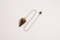Raw Earth Crystals tiger eye pendulum with pointed crystal and silver chain, crafted for confidence, focus, and grounding energy.