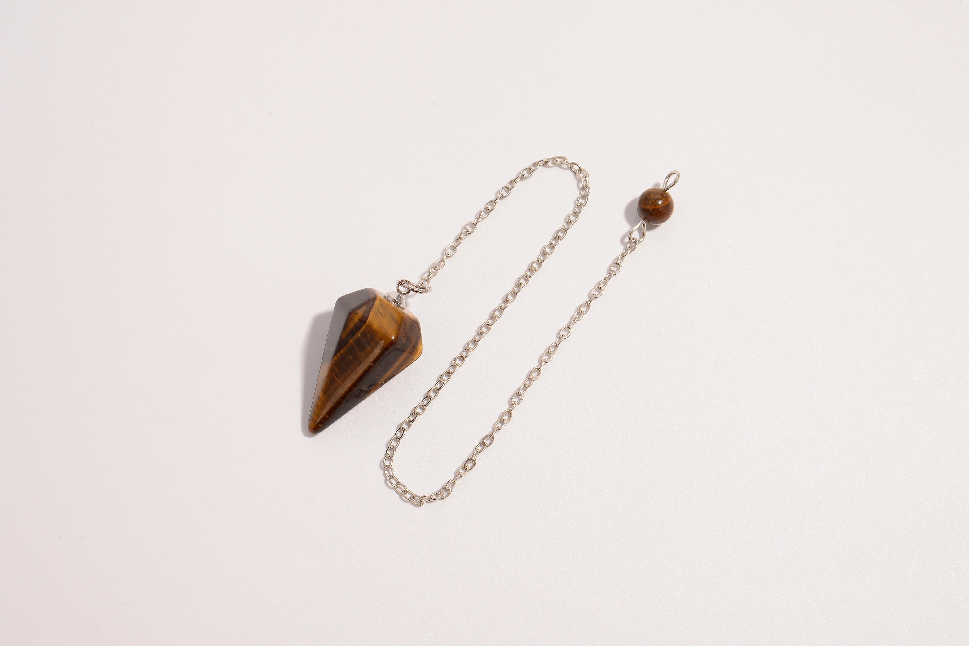 Raw Earth Crystals tiger eye pendulum with pointed crystal and silver chain, crafted for confidence, focus, and grounding energy.