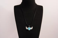 Raw Earth Crystals turquoise heart with wings necklace, featuring a vibrant blue-green heart-shaped stone adorned with delicate angelic wings, designed to promote communication, emotional balance, and spiritual protection.