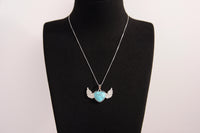 Raw Earth Crystals turquoise heart with wings necklace, featuring a vibrant blue-green heart-shaped stone adorned with delicate angelic wings, designed to promote communication, emotional balance, and spiritual protection.